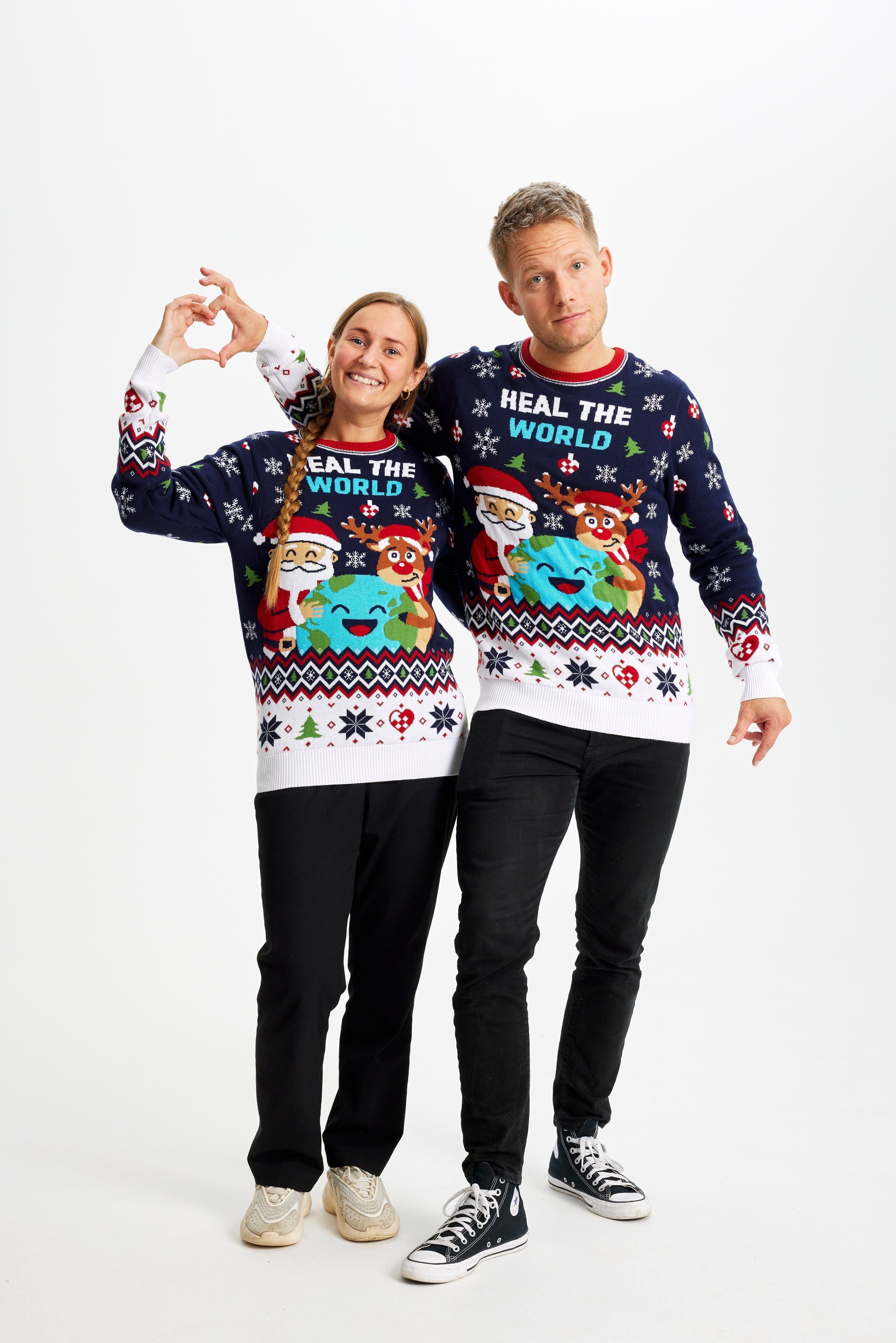 Un couple se tenant l'un l'autre, portant un pull de Noël bleu et blanc avec la citation